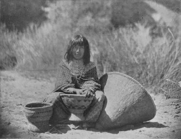 A YUMA WOMAN WEAVING COARSE BASKETS